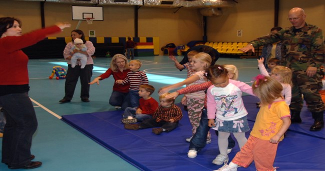 photo of children playing Hokey Pokey in a military gym