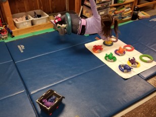 This photo shows the  swinging above the floor target and placing her toy into one of the rings.