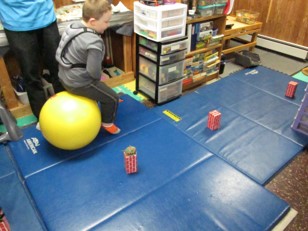 This photo shows a boy on a hop ball who is hopping around obstacles of an obstacle course.