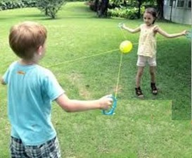 This photo shows children playing zoom ball on a lawn.  They are using their eyes to  follow the ball as it moves along the ropes from one child to another.