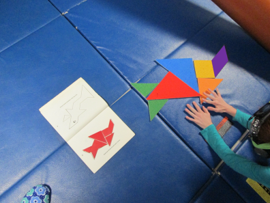 This photo shows  a child working on a tangram  puzzle 
