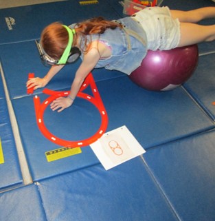 This girl is pushing the weight of her body up against gravity as she uses ball walkouts to assemble a track layout.