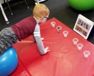 This young boy is pushing himself up against gravity on the Physioball  while he picks up and places each car into place as shown by the photo lineup.