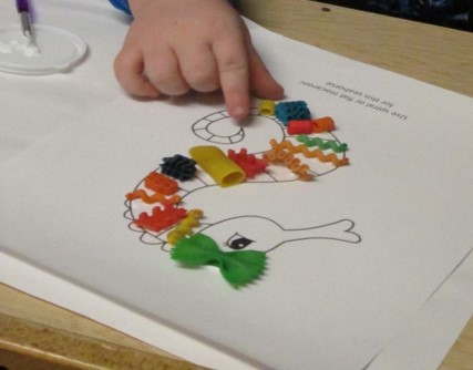 The youngster in the above photo is using Colored Macaroni to fill in a worksheet