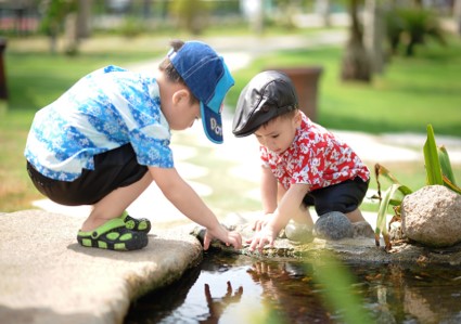 The photo shows two preschoolers looking into a pond