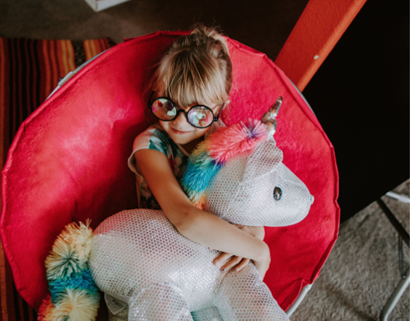 This photo shows a youngster who is seated with a stuffed weighted pet on her lap.